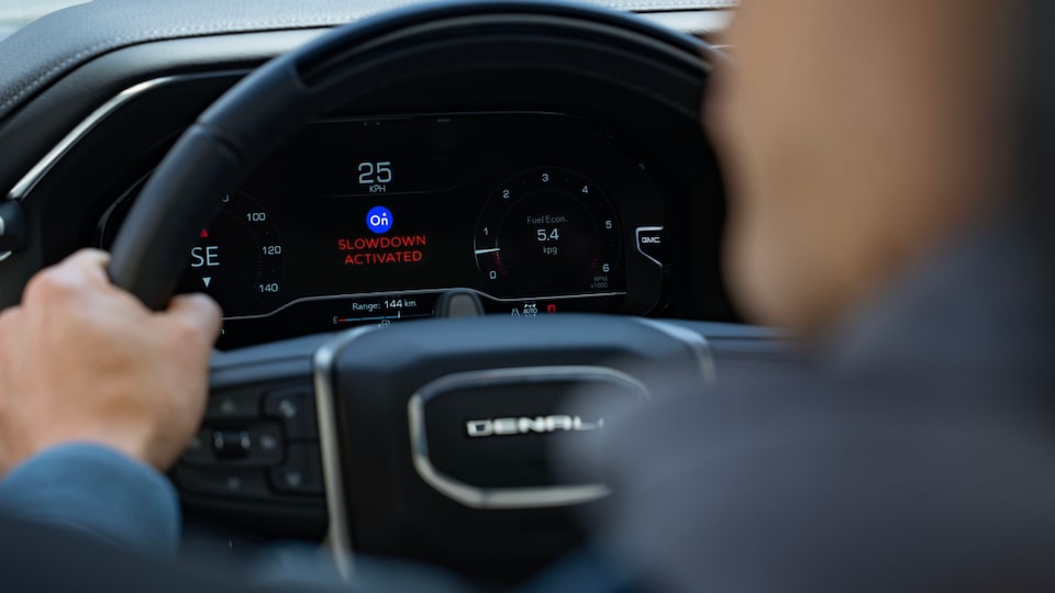 An over the shoulder view of a vehicle's steering wheel and dashboard