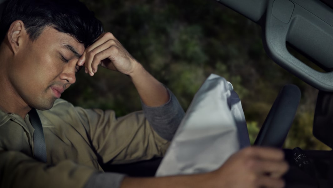 Man in car accident rests head on hand while waiting for OnStar.