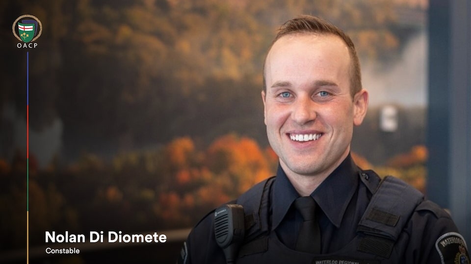 A smiling constable Nolan Di Diomete standing near a picture frame.