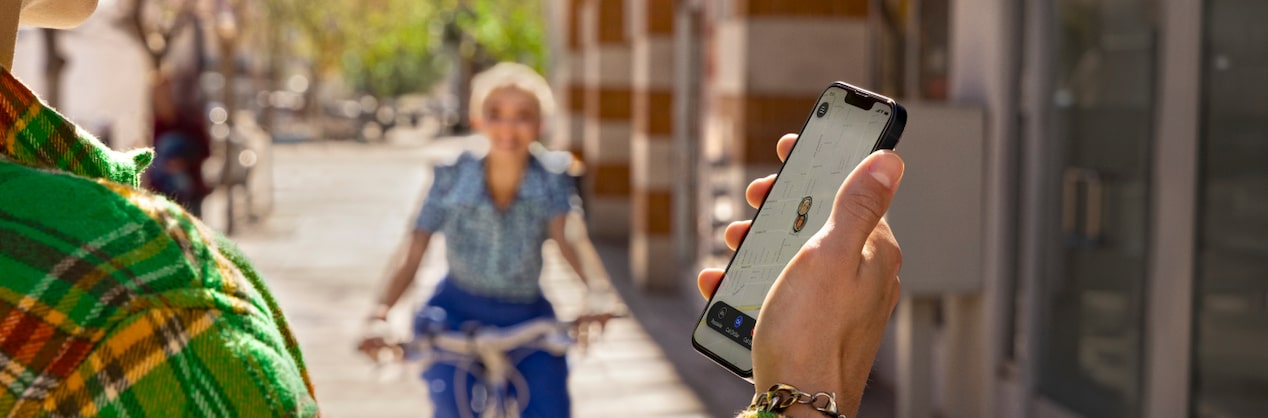 Une femme au loin roule en vélo vers un homme qui utilise l’application OnStar.