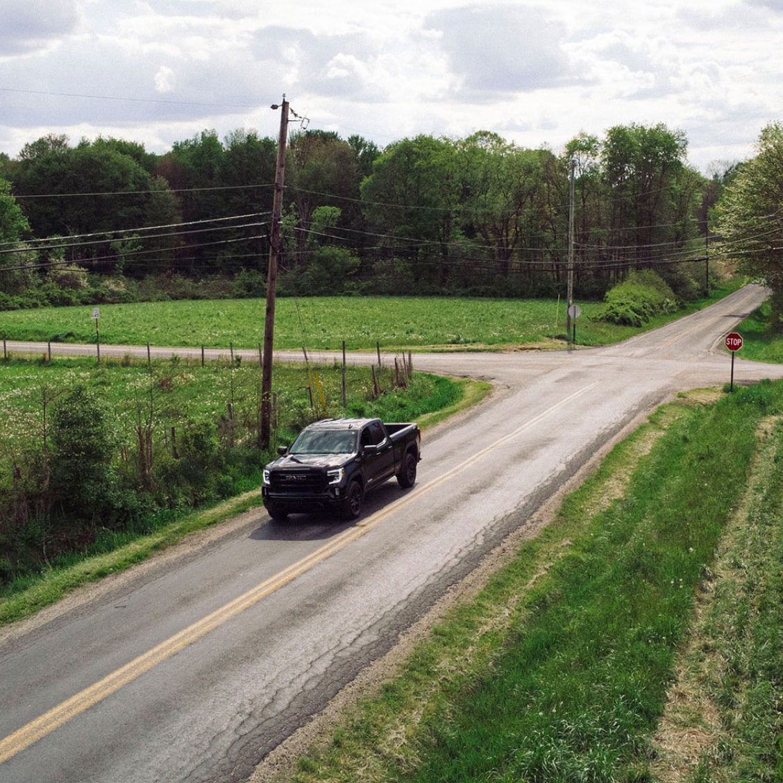 GM Truck Driving Through Small Town Roads With Green Grass.