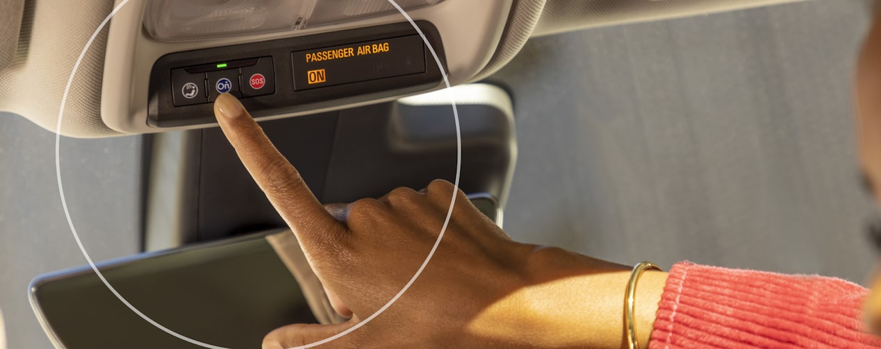 Close up view of a woman pressing the OnStar button.