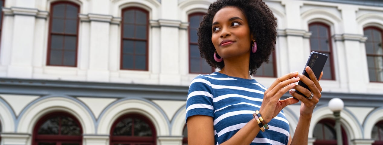 A woman holding her smartphone while anticipating OnStar's service to arrive at any moment.