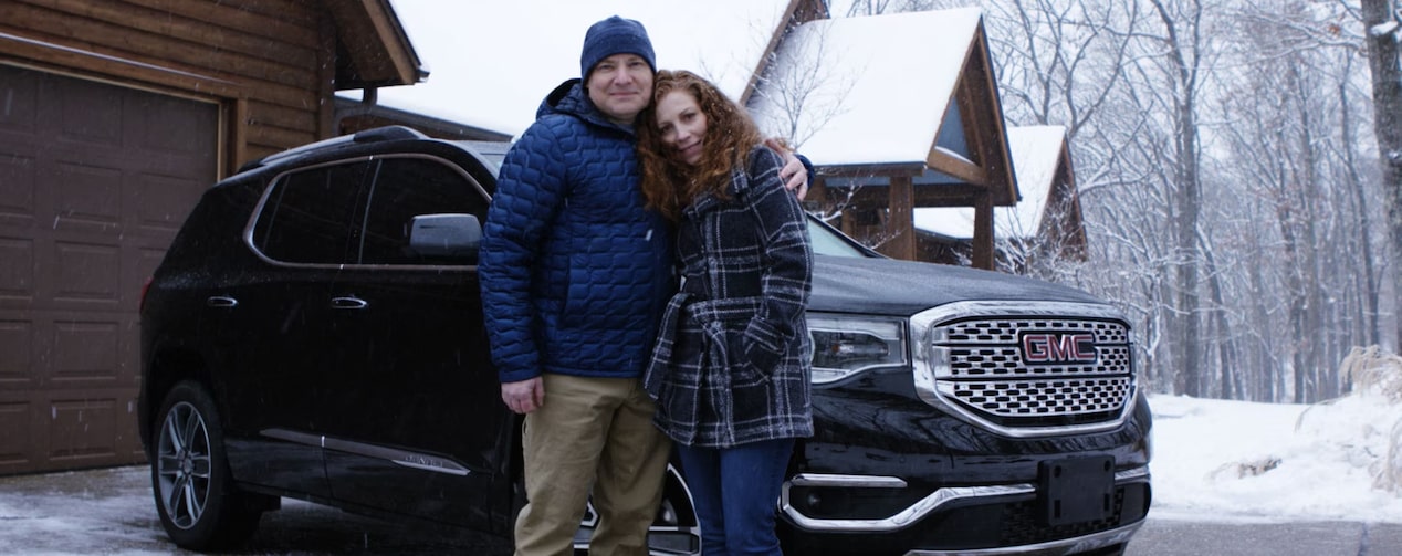 Tammy Chervitz and a man Stands in Front of GMC Acadia in Winter Weather.