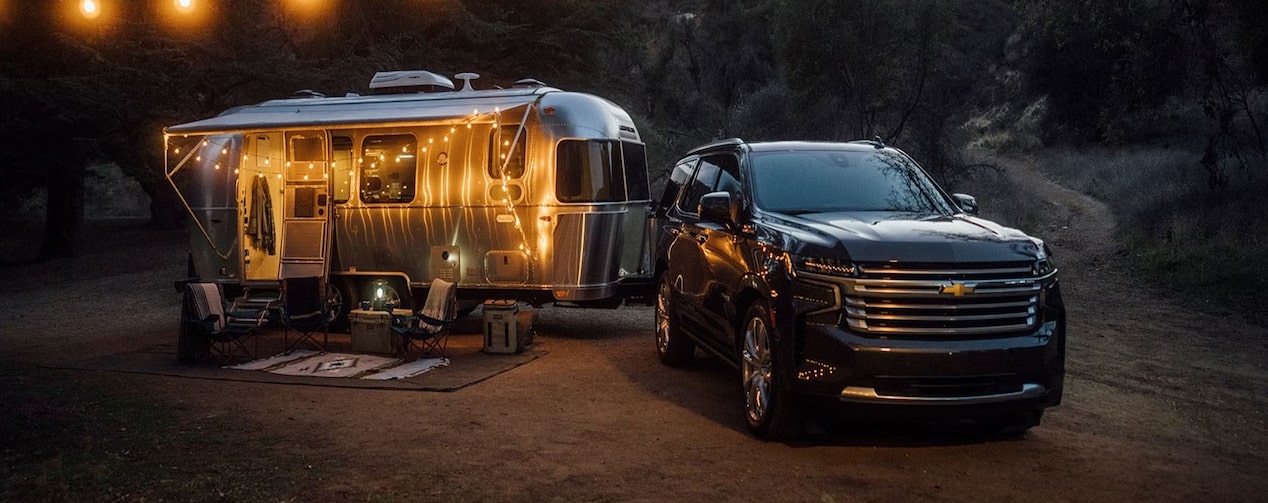 A Chevrolet Vehicle and a trailer parked for a wilderness vacation.