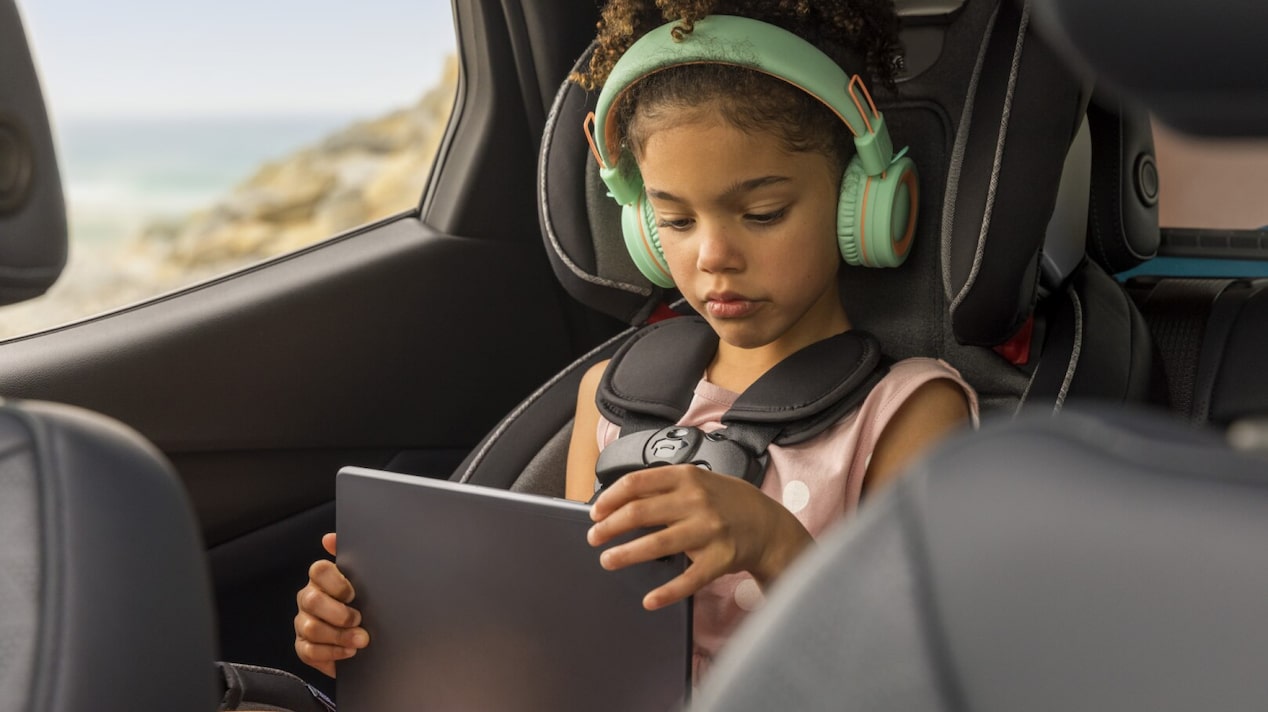 Enfant utilisant divers gadgets confortablement tout en conduisant en voiture.