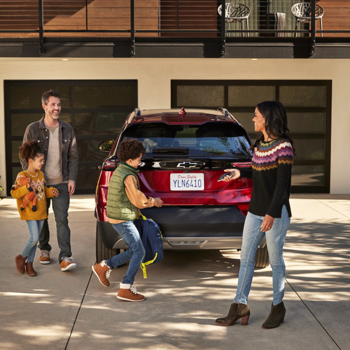 A jolly family about to enter their OnStar-subscribed vehicle on their home.