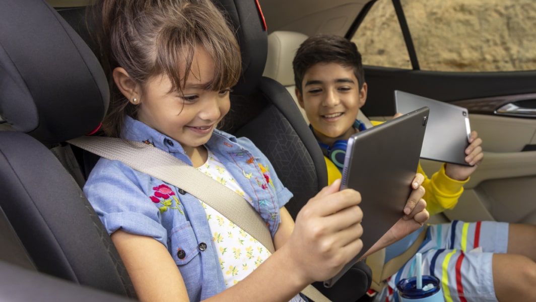 Two children using their tablets to access OnStar's HD streaming perk.