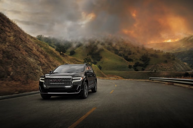 A GMC vehicle driving away from a wildfire.