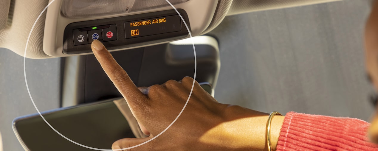 Close up of a person wearing red pressing the OnStar button.